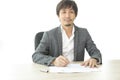 Middle age Asian businessman writing document report in the office. Signing contract. Royalty Free Stock Photo