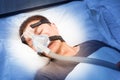 middle age asian man sleeping in his bed wearing CPAP mask connecting to air hose, device for people with sleep apnea Royalty Free Stock Photo