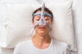 middle age asian man sleeping in his bed wearing CPAP mask connecting to air hose, device for people with sleep apnea Royalty Free Stock Photo