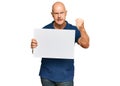 Middle age bald man holding blank empty banner annoyed and frustrated shouting with anger, yelling crazy with anger and hand Royalty Free Stock Photo