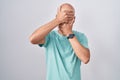 Middle age bald man standing over white background covering eyes and mouth with hands, surprised and shocked Royalty Free Stock Photo