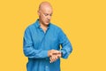 Middle age bald man wearing casual clothes checking the time on wrist watch, relaxed and confident