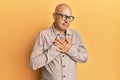 Middle age bald man wearing casual clothes and glasses smiling with hands on chest with closed eyes and grateful gesture on face Royalty Free Stock Photo