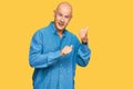 Middle age bald man wearing casual clothes pointing to the back behind with hand and thumbs up, smiling confident Royalty Free Stock Photo