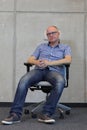 Middle age balding man with eyeglasses bad sitting position on chair in office Royalty Free Stock Photo