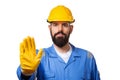 Middle age bearded workman with yellow helmet and uniform making stop gesture with his hand denying a situation that could wrong.