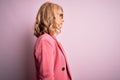 Middle age beautiful blonde business woman wearing elegant pink jacket and glasses looking to side, relax profile pose with Royalty Free Stock Photo