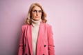 Middle age beautiful blonde business woman wearing elegant pink jacket and glasses with serious expression on face Royalty Free Stock Photo