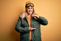 Middle age beautiful blonde skier woman wearing snow sportwear and ski goggles gesturing with hands showing big and large size