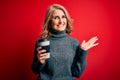 Middle age beautiful blonde woman drinking takeaway cup of coffee over red background very happy and excited, winner expression Royalty Free Stock Photo