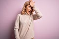 Middle age beautiful blonde woman wearing casual turtleneck sweater over pink background surprised with hand on head for mistake, Royalty Free Stock Photo