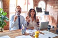 Middle age beautiful business workers working together using laptop at the office amazed and surprised looking up and pointing Royalty Free Stock Photo