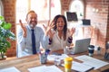 Middle age beautiful business workers working together using laptop at the office celebrating mad and crazy for success with arms Royalty Free Stock Photo