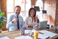 Middle age beautiful business workers working together using laptop at the office doing happy thumbs up gesture with hand Royalty Free Stock Photo