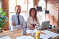 Middle age beautiful business workers working together using laptop at the office happy face smiling with crossed arms looking at Royalty Free Stock Photo