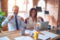 Middle age beautiful business workers working together using laptop at the office looking confident with smile on face, pointing Royalty Free Stock Photo