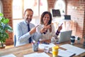 Middle age beautiful business workers working together using laptop at the office smiling and looking at the camera pointing with Royalty Free Stock Photo