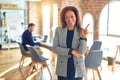 Middle age beautiful businesswoman wearing jacket and glasses standing at the office with a big smile on face, pointing with hand Royalty Free Stock Photo