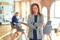 Middle age beautiful businesswoman wearing jacket and glasses standing at the office happy face smiling with crossed arms looking Royalty Free Stock Photo