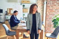 Middle age beautiful businesswoman wearing jacket and glasses standing at the office looking away to side with smile on face, Royalty Free Stock Photo