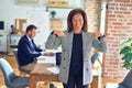 Middle age beautiful businesswoman wearing jacket and glasses standing at the office looking confident with smile on face, Royalty Free Stock Photo