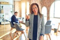 Middle age beautiful businesswoman wearing jacket and glasses standing at the office smiling with happy face looking and pointing Royalty Free Stock Photo