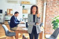 Middle age beautiful businesswoman wearing jacket and glasses standing at the office smiling with happy face looking and pointing Royalty Free Stock Photo
