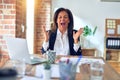 Middle age beautiful businesswoman working using laptop at the office celebrating mad and crazy for success with arms raised and Royalty Free Stock Photo