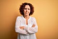 Middle age beautiful curly hair woman wearing casual summer dress over yellow background skeptic and nervous, disapproving Royalty Free Stock Photo