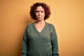 Middle age beautiful curly hair woman wearing casual sweater over isolated yellow background depressed and worry for distress, Royalty Free Stock Photo