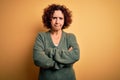 Middle age beautiful curly hair woman wearing casual sweater over isolated yellow background skeptic and nervous, disapproving Royalty Free Stock Photo