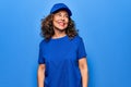 Middle age beautiful delivery woman wearing blue uniform and cap over isolated background looking to side, relax profile pose with Royalty Free Stock Photo