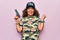 Middle age beautiful hunter woman wearing camouflage t-shirt and usa cap holding gun screaming proud, celebrating victory and Royalty Free Stock Photo
