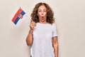 Middle age beautiful patriotic woman holding serbian flag over isolated white background scared and amazed with open mouth for Royalty Free Stock Photo