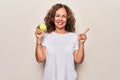 Middle age beautiful  sportswoman holding tennis ball over isolated white background smiling happy pointing with hand and finger Royalty Free Stock Photo