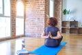 Middle age beautiful sportwoman sitting on mat on backview practicing yoga doing reverse prayer pose at gym Royalty Free Stock Photo