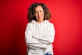 Middle age beautiful sporty woman wearing white sweatshirt over isolated red background happy face smiling with crossed arms Royalty Free Stock Photo