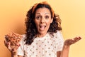 Middle age beautiful woman holding bowl with almonds celebrating achievement with happy smile and winner expression with raised Royalty Free Stock Photo