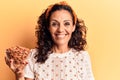 Middle age beautiful woman holding bowl with almonds looking positive and happy standing and smiling with a confident smile Royalty Free Stock Photo