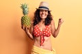 Middle age beautiful woman wearing bikini and summer hat holding pineappel screaming proud, celebrating victory and success very Royalty Free Stock Photo