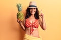 Middle age beautiful woman wearing bikini and summer hat holding pineappel smiling with an idea or question pointing finger with Royalty Free Stock Photo