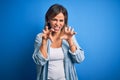 Middle age beautiful woman wearing casual shirt standing over isolated blue background smiling funny doing claw gesture as cat, Royalty Free Stock Photo