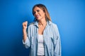 Middle age beautiful woman wearing casual shirt standing over isolated blue background smiling with happy face looking and Royalty Free Stock Photo