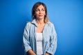 Middle age beautiful woman wearing casual shirt standing over isolated blue background smiling looking to the side and staring Royalty Free Stock Photo