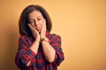 Middle age beautiful woman wearing casual shirt standing over isolated yellow background Tired hands covering face, depression and Royalty Free Stock Photo