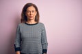 Middle age beautiful woman wearing casual sweater standing over isolated pink background with serious expression on face Royalty Free Stock Photo