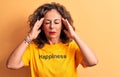 Middle age beautiful woman wearing t-shirt with happiness word over yellow background with hand on head, headache because stress