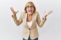 Middle age blonde business woman standing over isolated background celebrating crazy and amazed for success with arms raised and Royalty Free Stock Photo