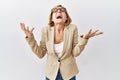 Middle age blonde business woman standing over isolated background celebrating mad and crazy for success with arms raised and Royalty Free Stock Photo