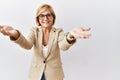 Middle age blonde business woman standing over isolated background looking at the camera smiling with open arms for hug Royalty Free Stock Photo